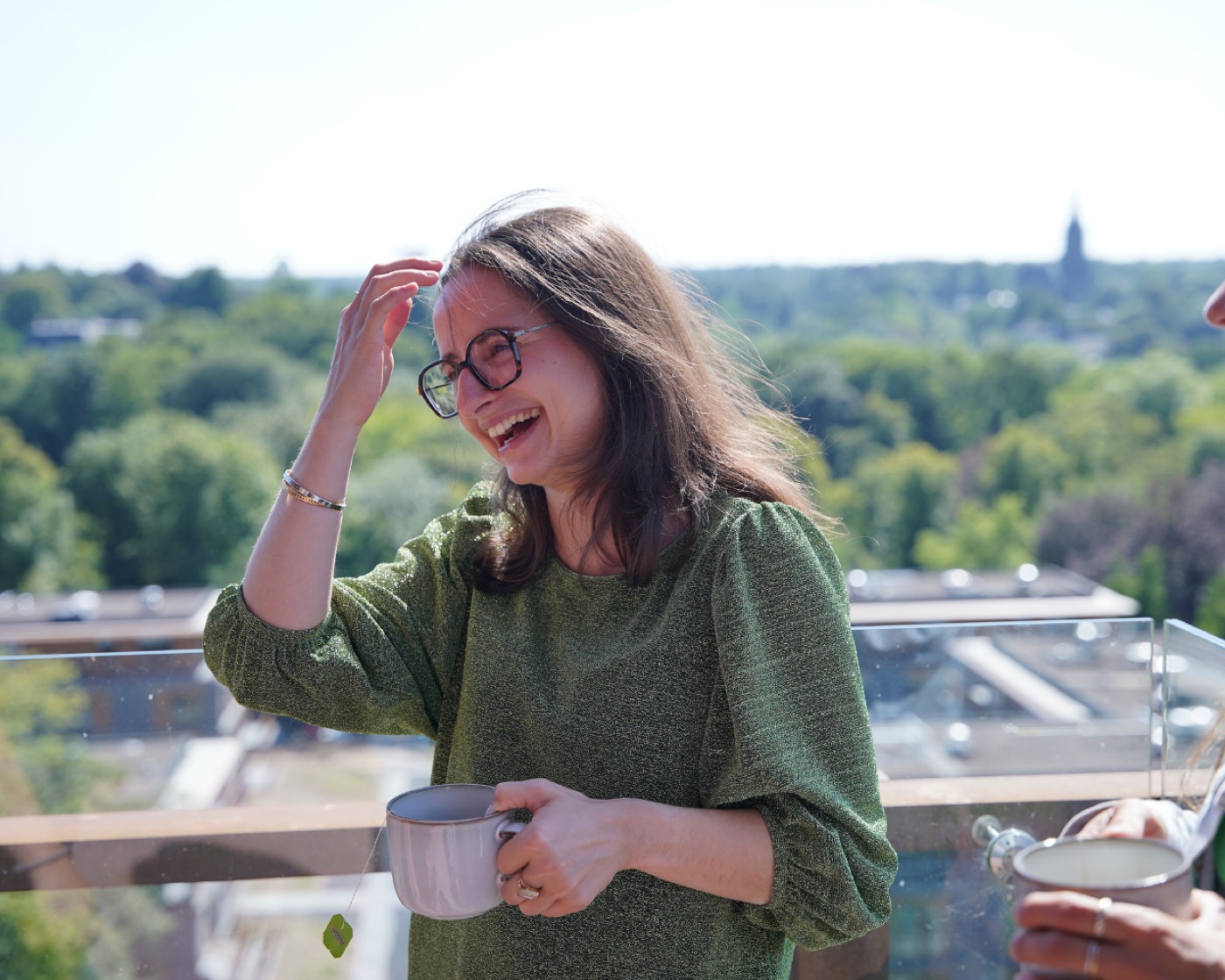 A Hi Folks team member laughing over coffee on the rooftop terrace